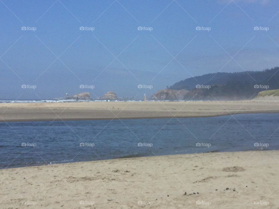 The white sand along Cannon Beach withe the tide out and mountains and rock formations in the distance 