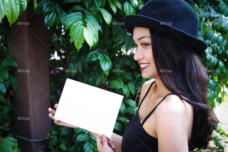 Attractive young women holding a blank white paper. 
