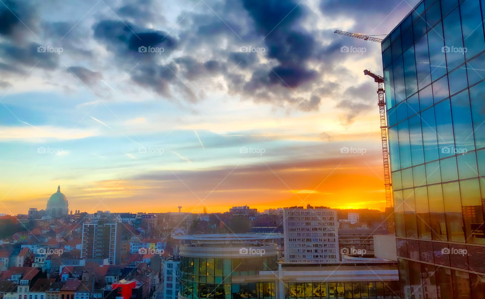 Colorful sunrise and dark dramatic clouds over the business district of the city and reflected in the windows of the office buildings