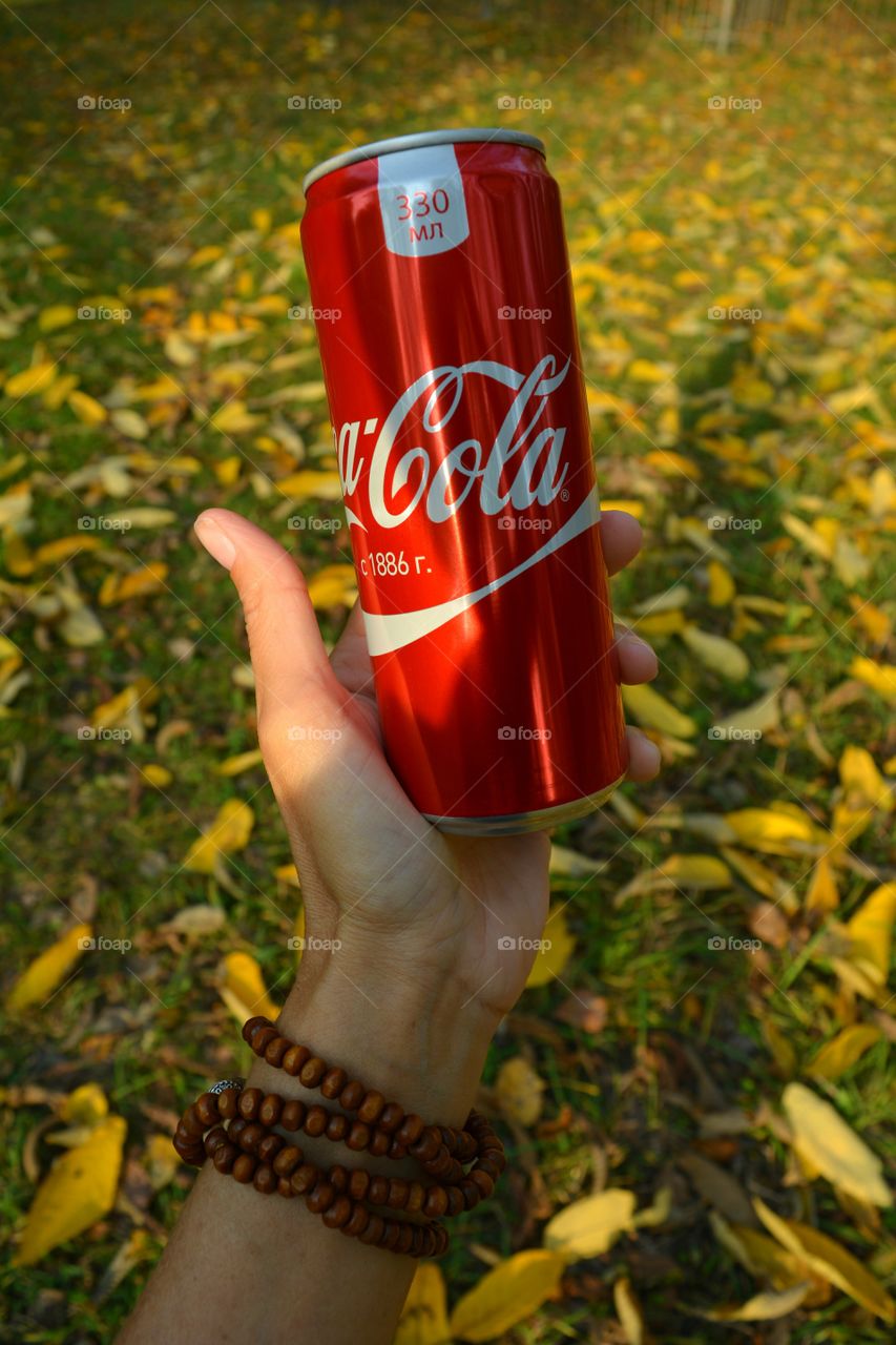 coca cola in hand autumn background, drinking coca cola outdoor