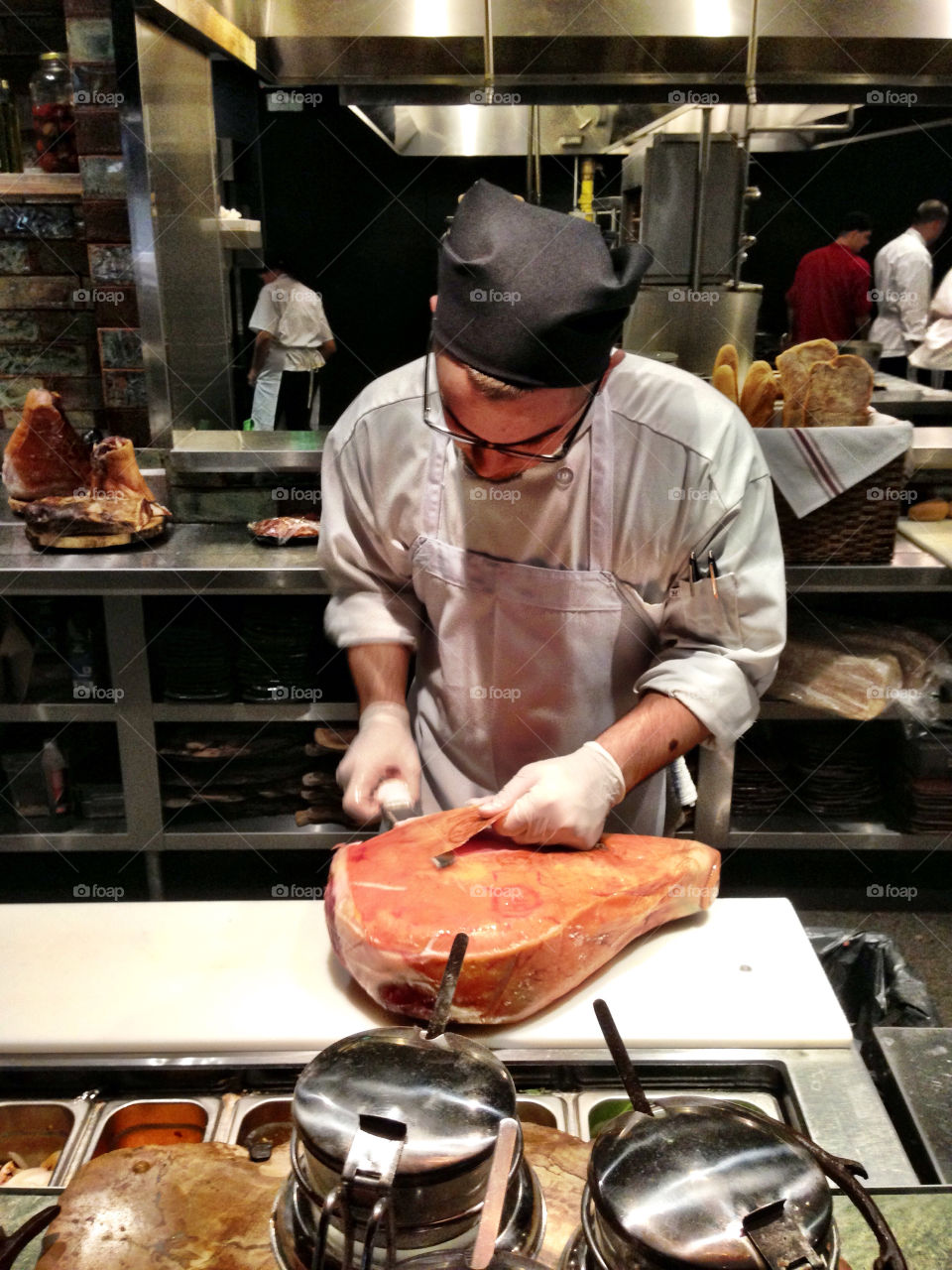 Man cutting prosciutto in restaurant