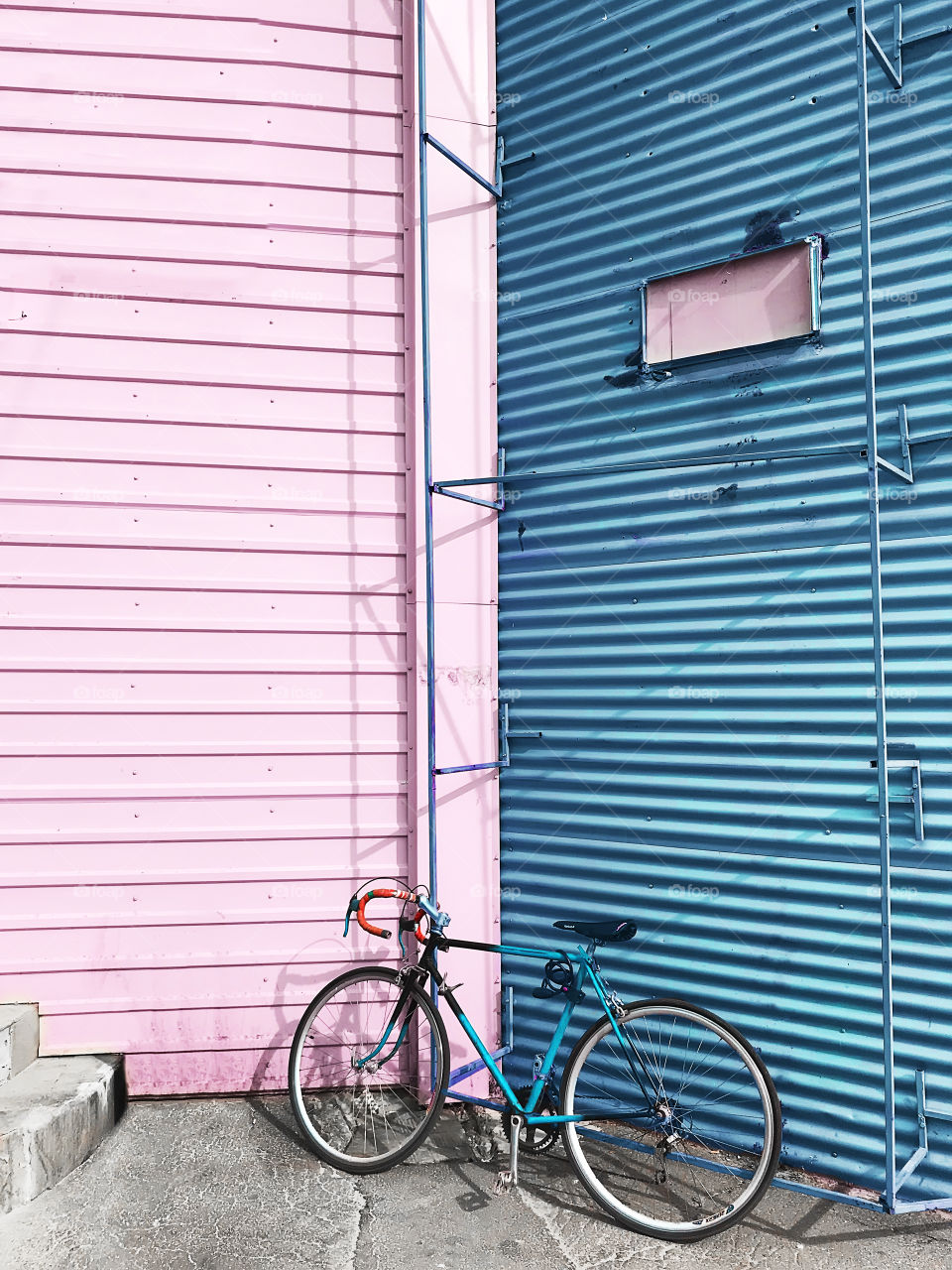 Bicycle standing in front of pink and blue pastel wall background 