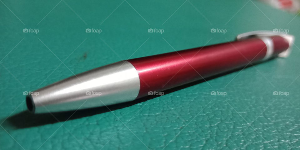 The macro view of red pen on green surface