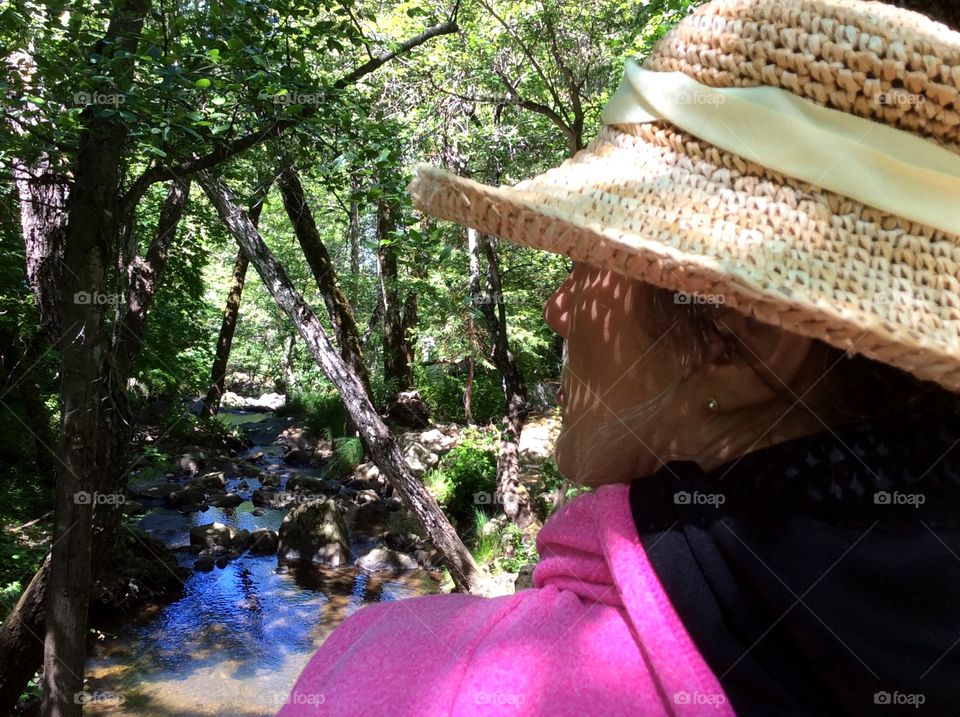 Sky blue reflections in Brook, woman in straw hat reflecting. Woman with straw hat in forest, viewing Brook reflecting blue sky