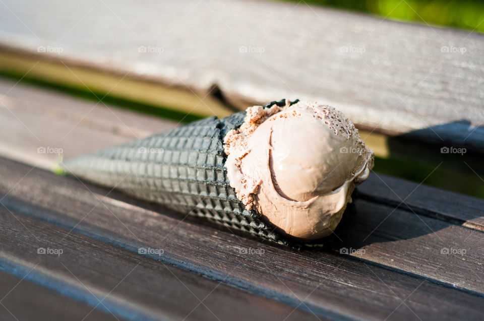Chocolate ice cream cone on wooden bench