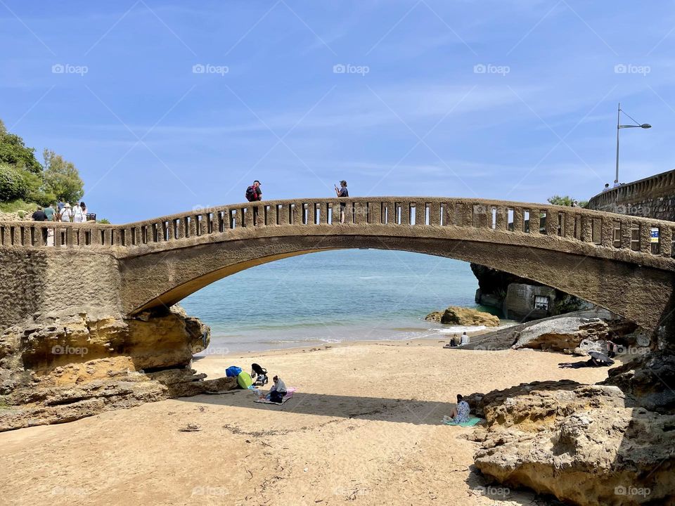 Low angle view of people on bridge by sea. 