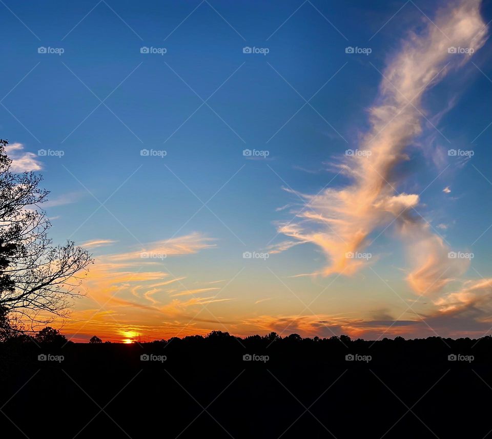 The sun reflecting off the clouds surrounding it and the clouds scattered throughout the sky bringing to close a beautiful November day.