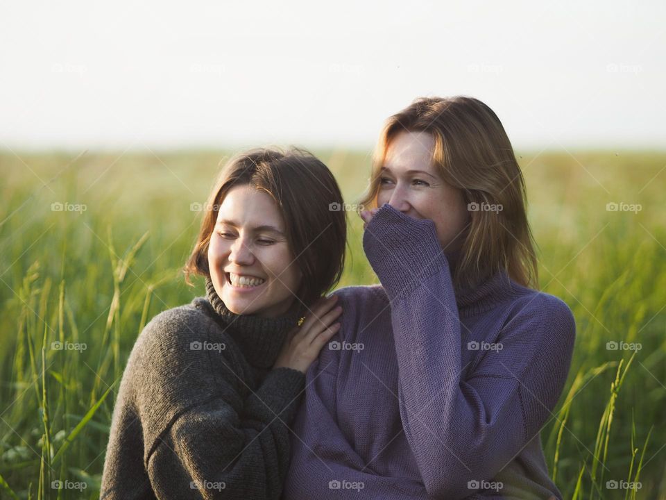 Two young beautiful woman’s standing in field in sunny summer day, portrait of woman, laughing 