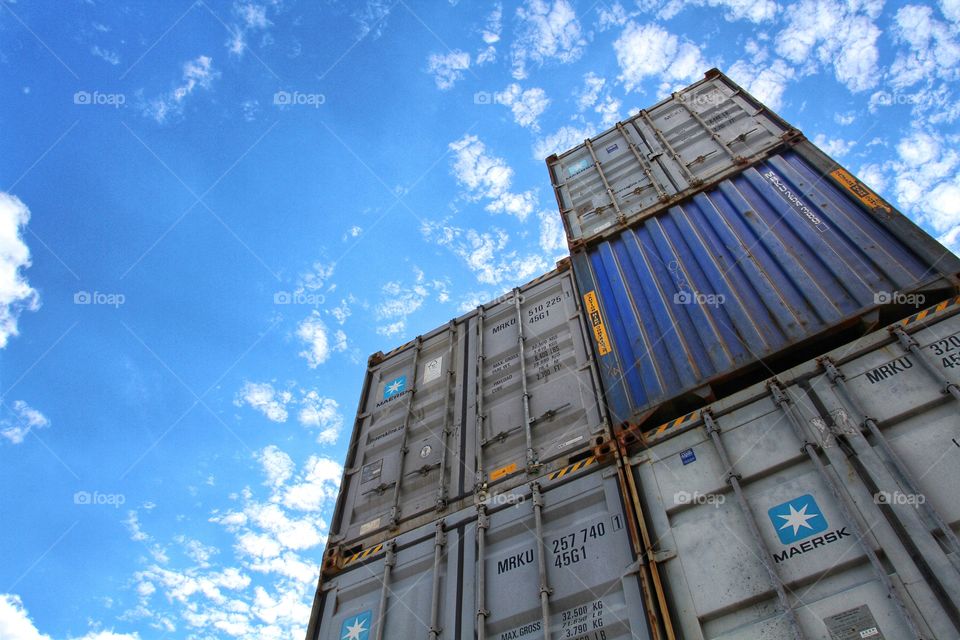 Looking up at shipping containers stacked up on top of each other under a blue sky.