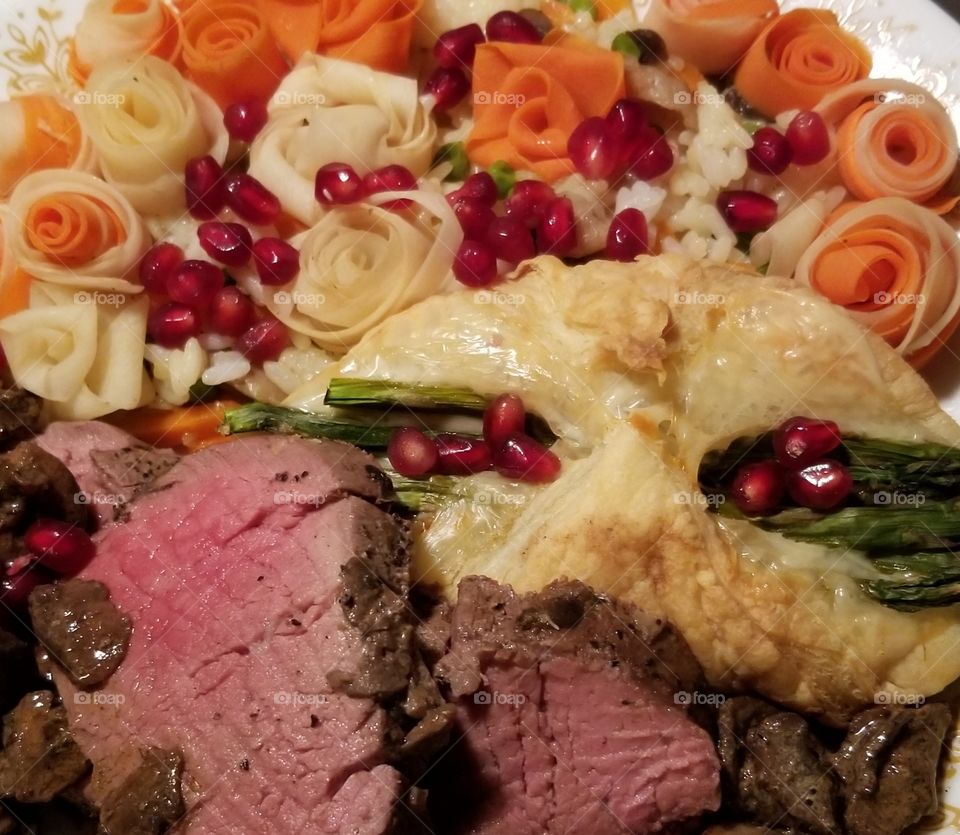 Roast Beef tenderloin with vegetable flowers, asparagus and gruyere en croute and pomegranate arils.