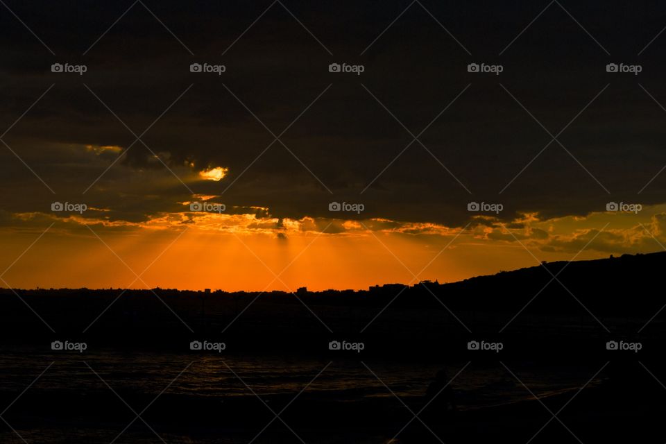 Last rays of sunset breaking through heavy cloud. Limassol, Cyprus