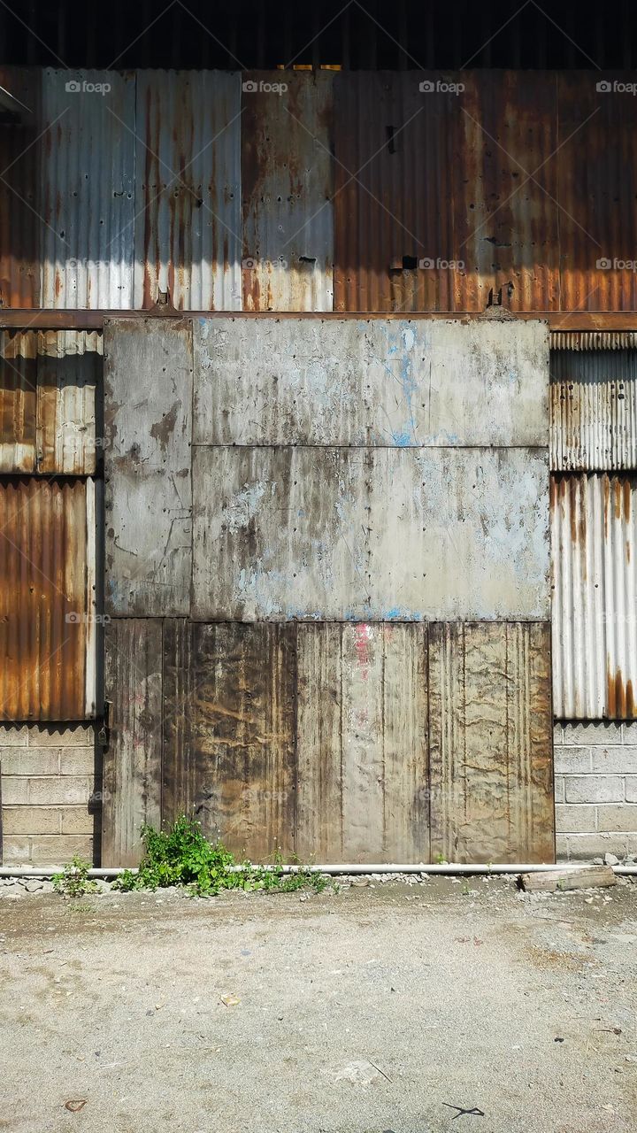 Old building covered with rusty corrugated tin walls and rolling door.