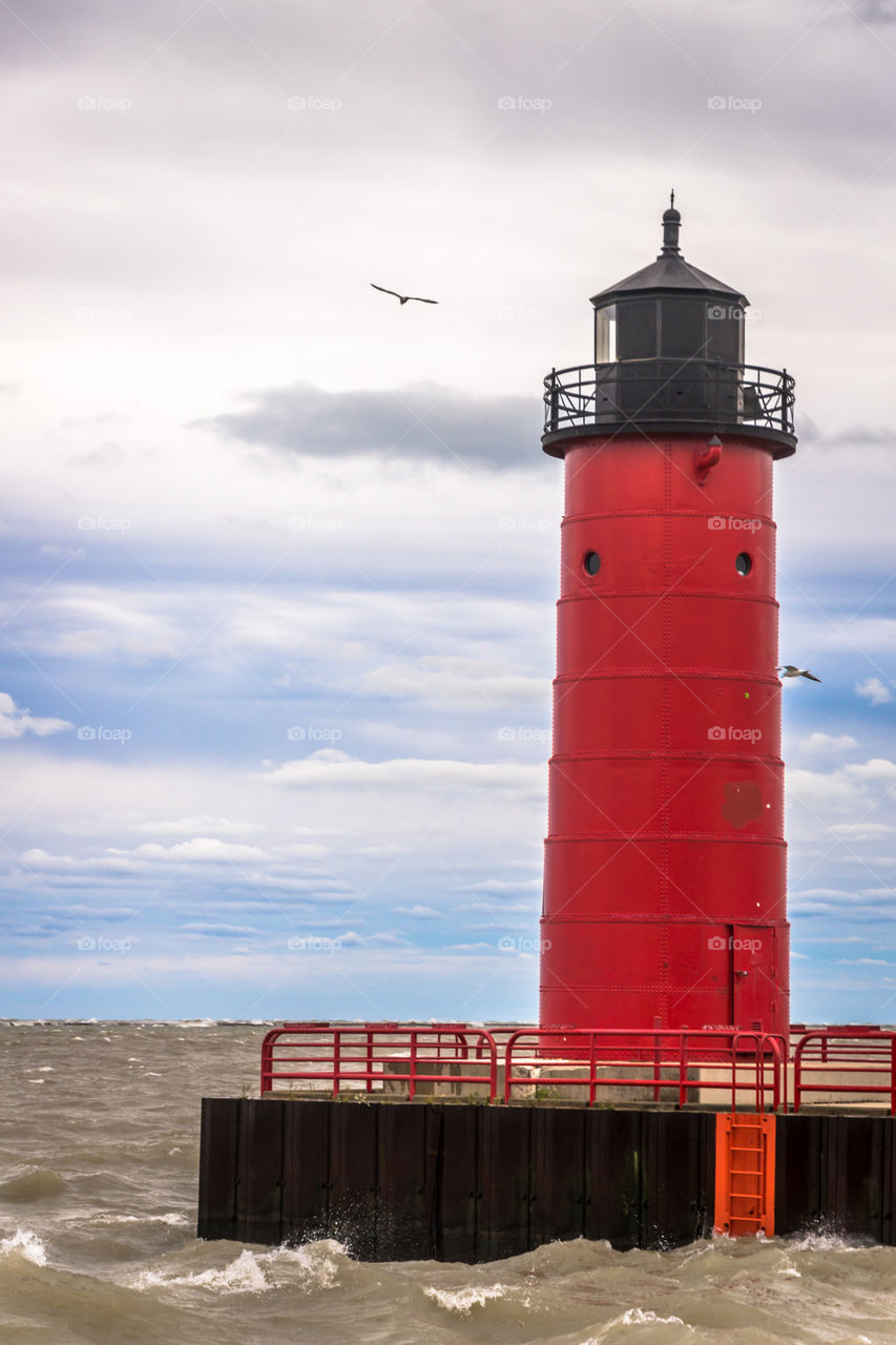 Red lighthouse in WI. Red lighthouse at end of pier on Lake Michigan in Milwaukee Wisconsin during a wind storm