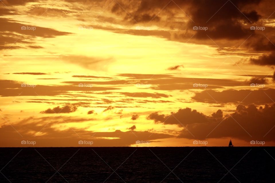 Sailboat on horizon as sunset in Castries, St. Lucia