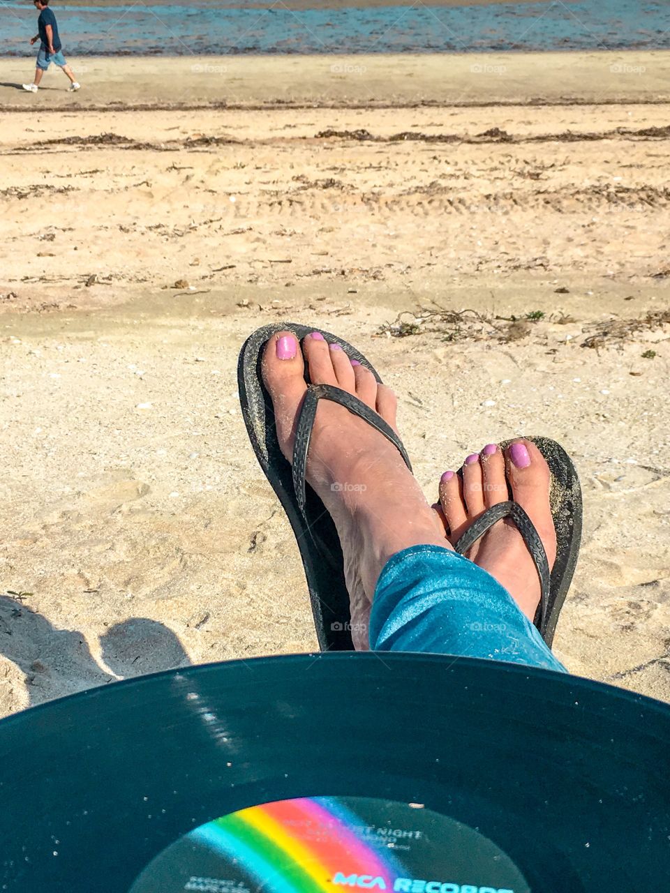 Vinyl record LP at beach, on lap, woman in jeans legs and feet only 