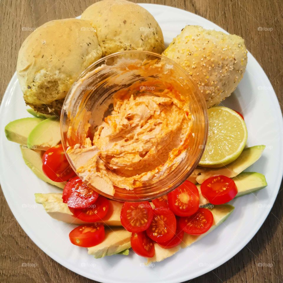 Fresh avocado and cherry tomatoes with homemade hummus and basil bread