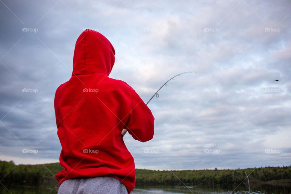 Person wearing red hoodie holding a fishing rod.
