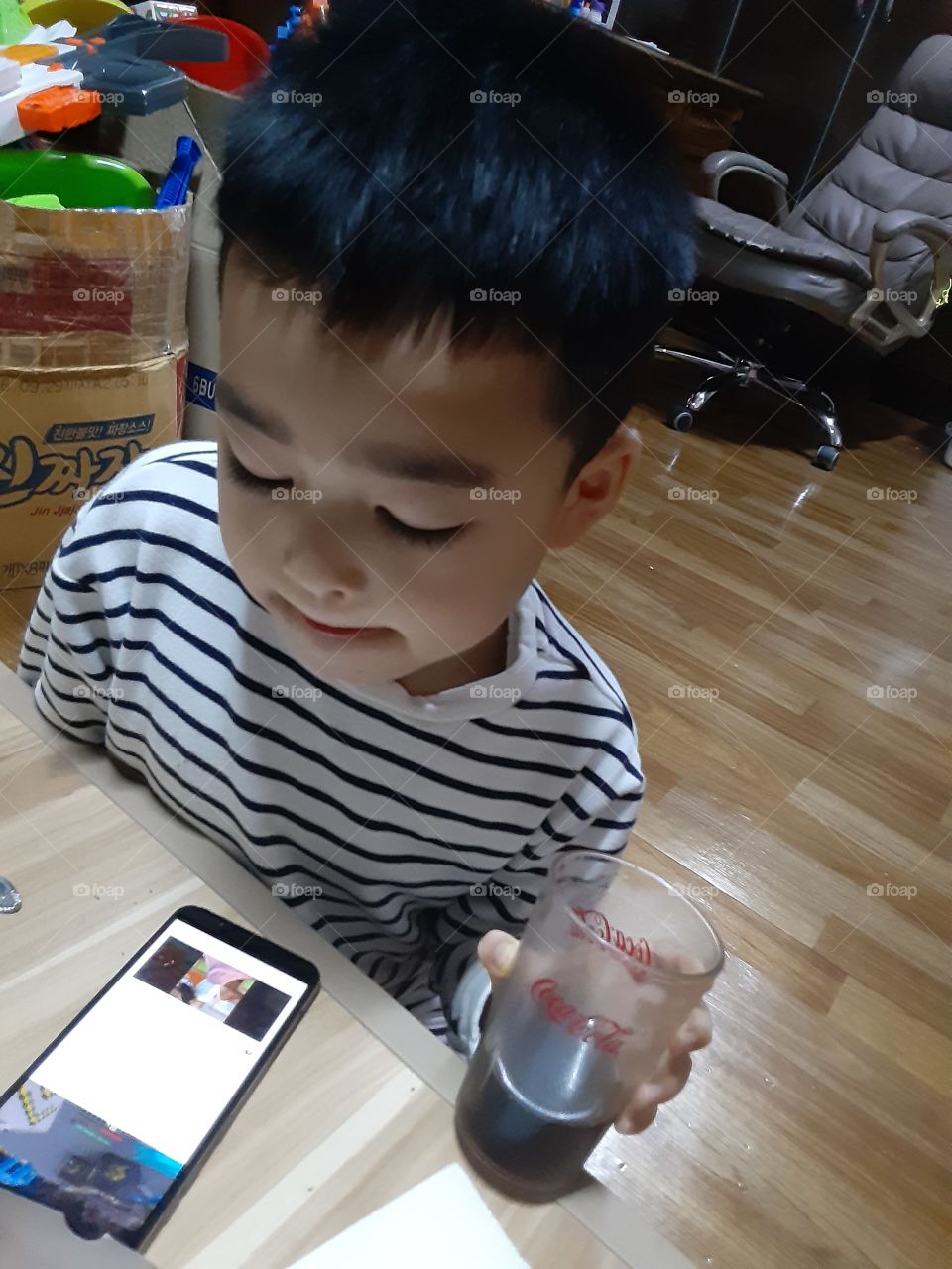busy with his fone while holding his favorate coca cola