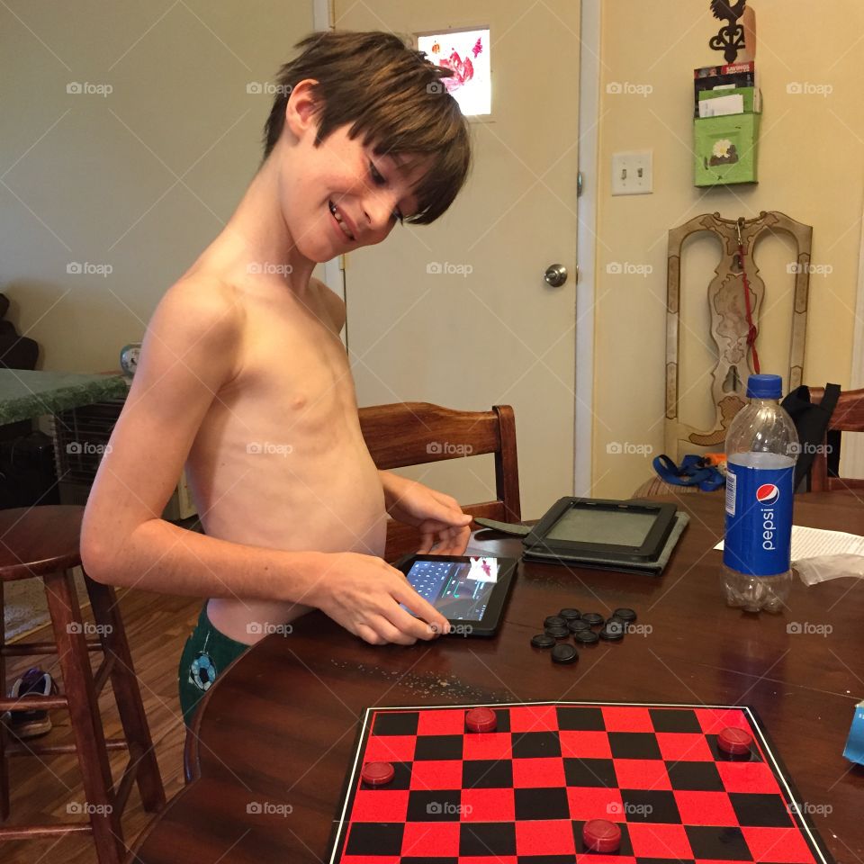 Young boy playing checker game at the table.
