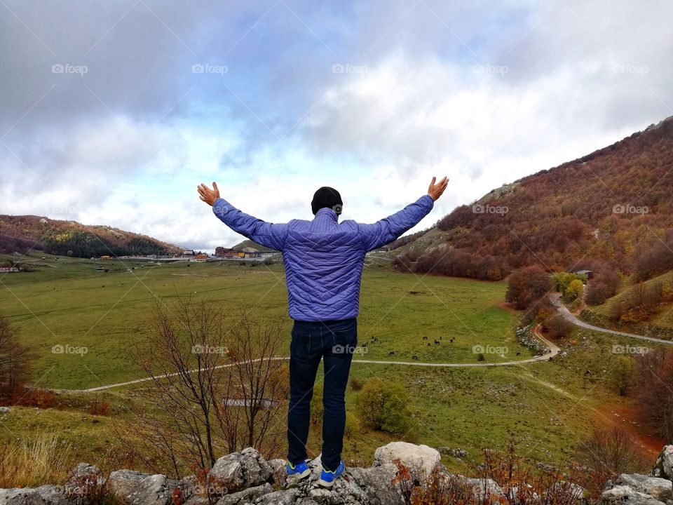 man from behind with open arms enjoys nature in solitude