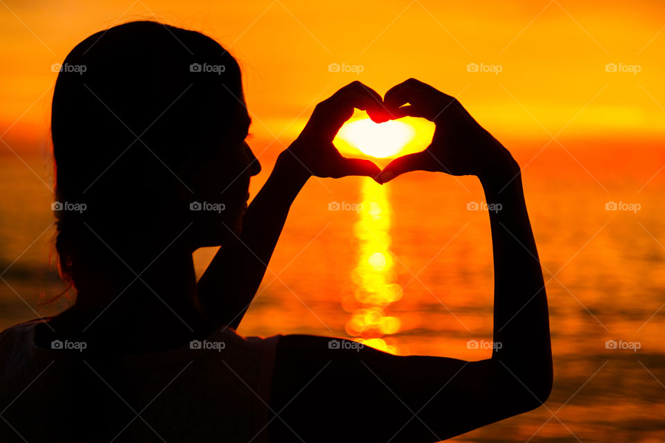 Silhouette of young woman on the sunset beach 