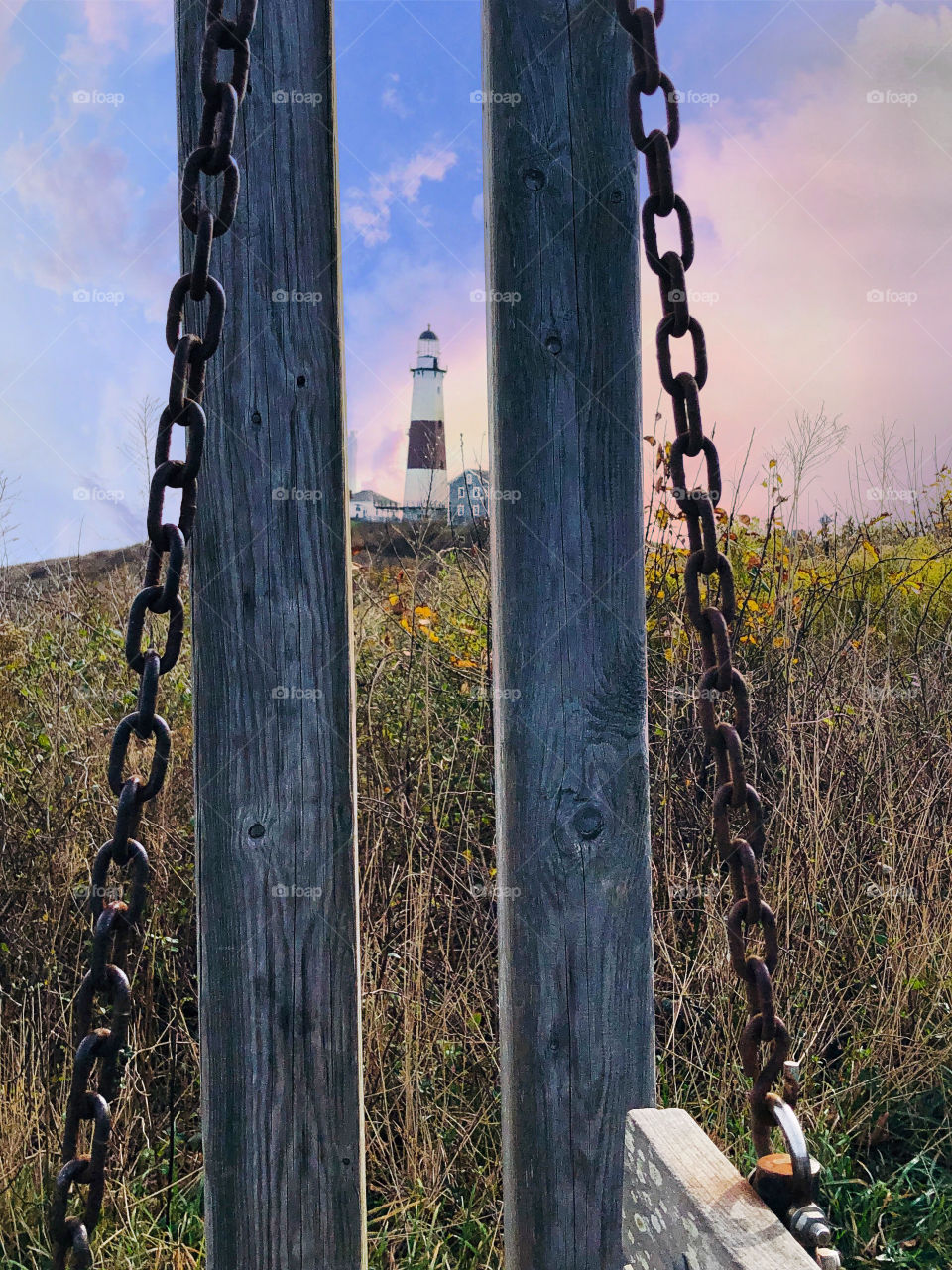 Perspective looking at lighthouse through wooden swing chains