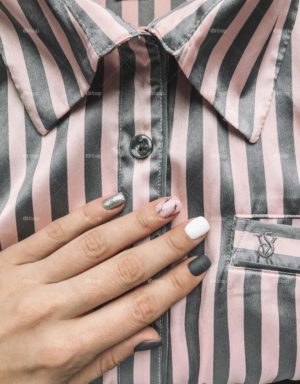 Woman manicure against striped pink background. Female beautiful nails. 