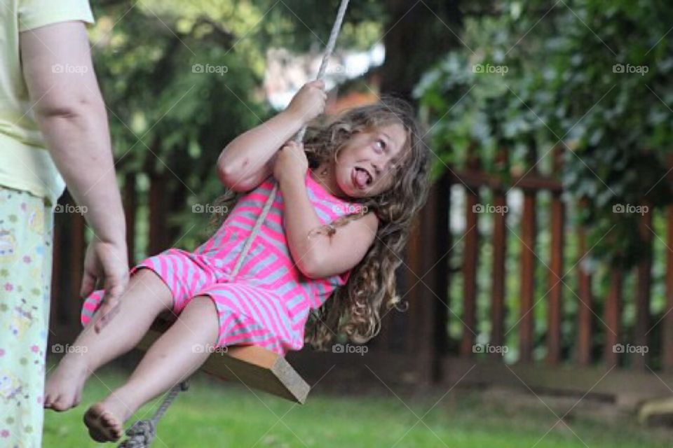 Little girl enjoying on rope swing in park