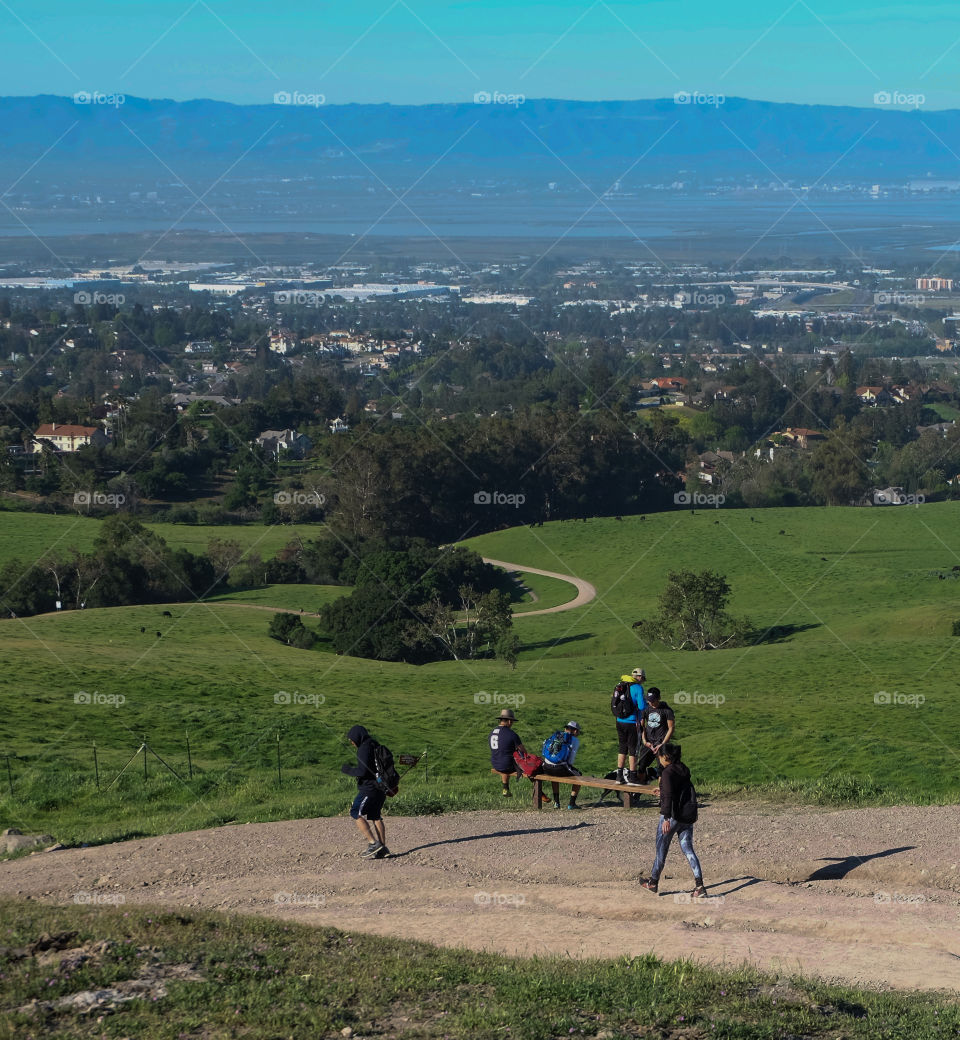 Hikers walking and resting, winding hiking trail, city down the valley in view