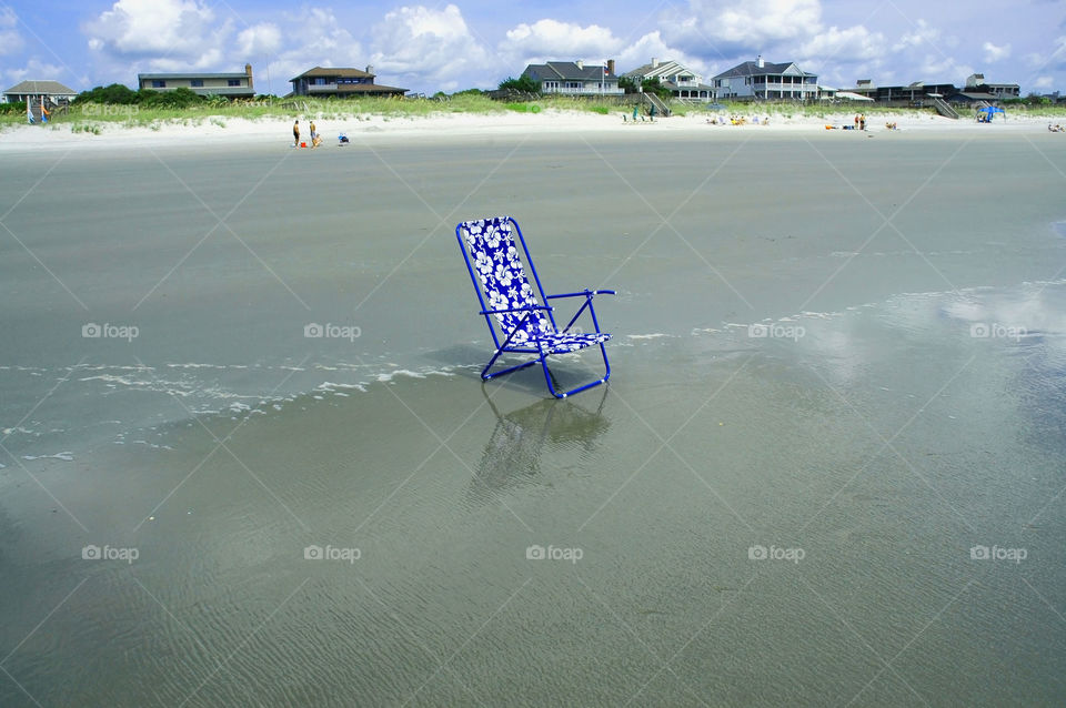 Beach chair. A pretty beach scene with a blue beach chair sitting in the surf