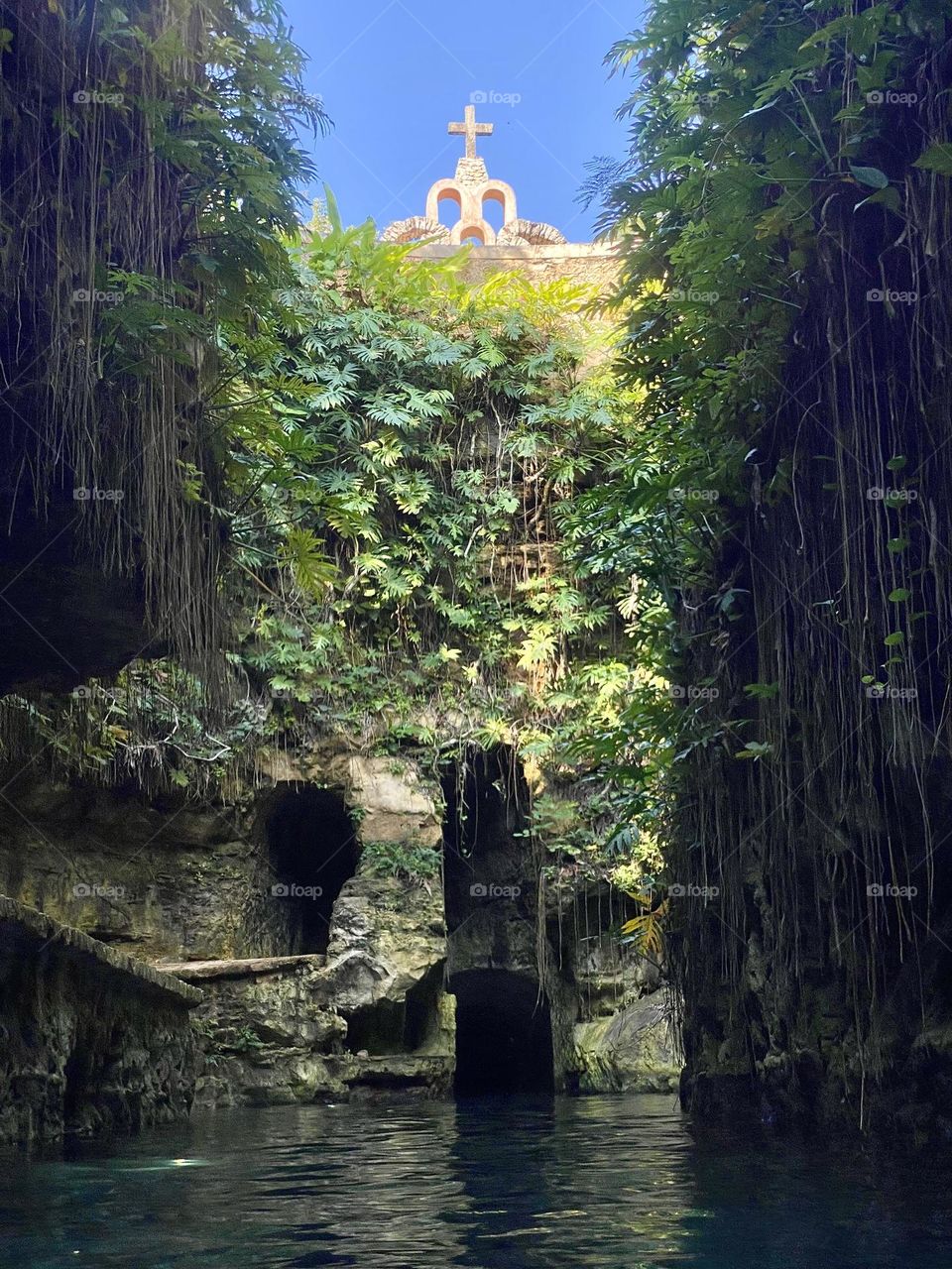Looking up towards a hacienda from the bottom of a cenote