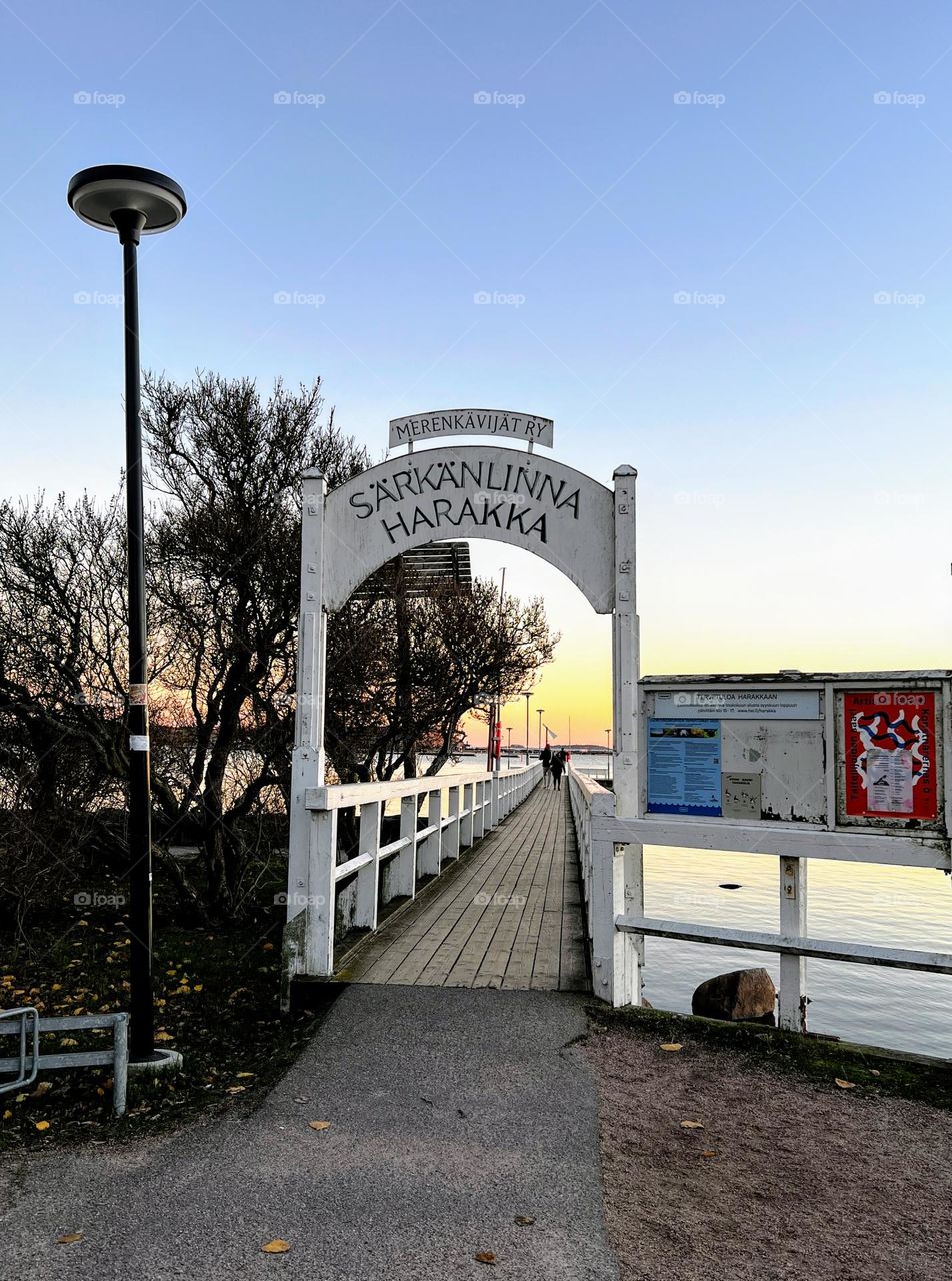 The gateway to the little local archipelago boat pier along the wooden walking bridge with white handrails 