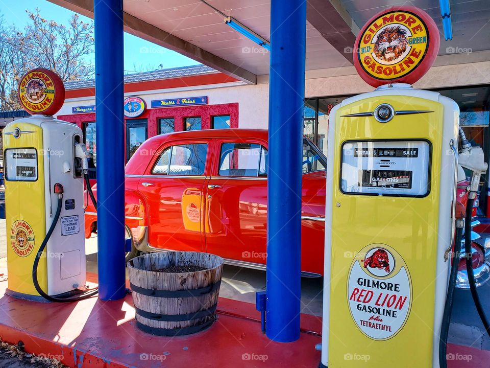 An old gas station has been converted into a fun and colorful restaurant complete with old car and gas pumps