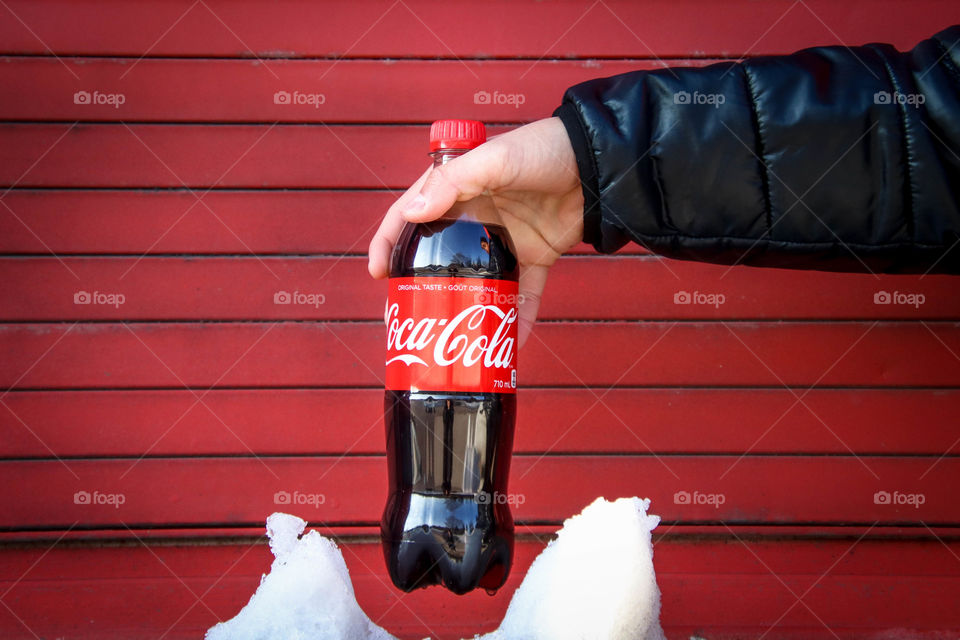 Man's hand holding a bottle of a Coca-Cola