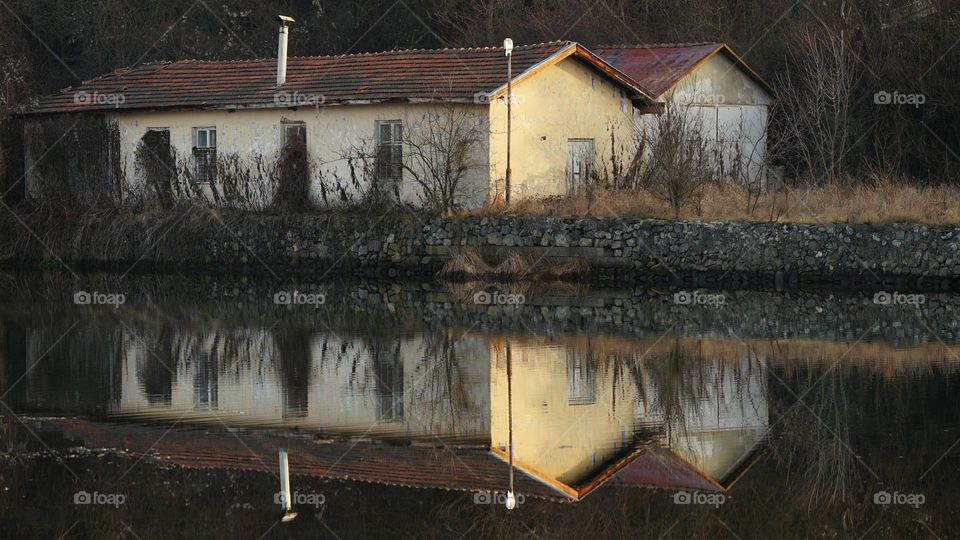Old house by the river with reflection