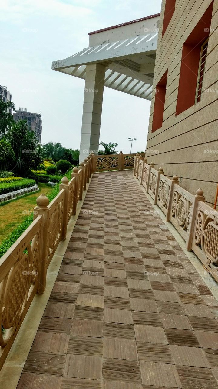 Beautifully constructed pathway having many geometrical designs.Floor has too many squares, railing and roof slope has rectangles.