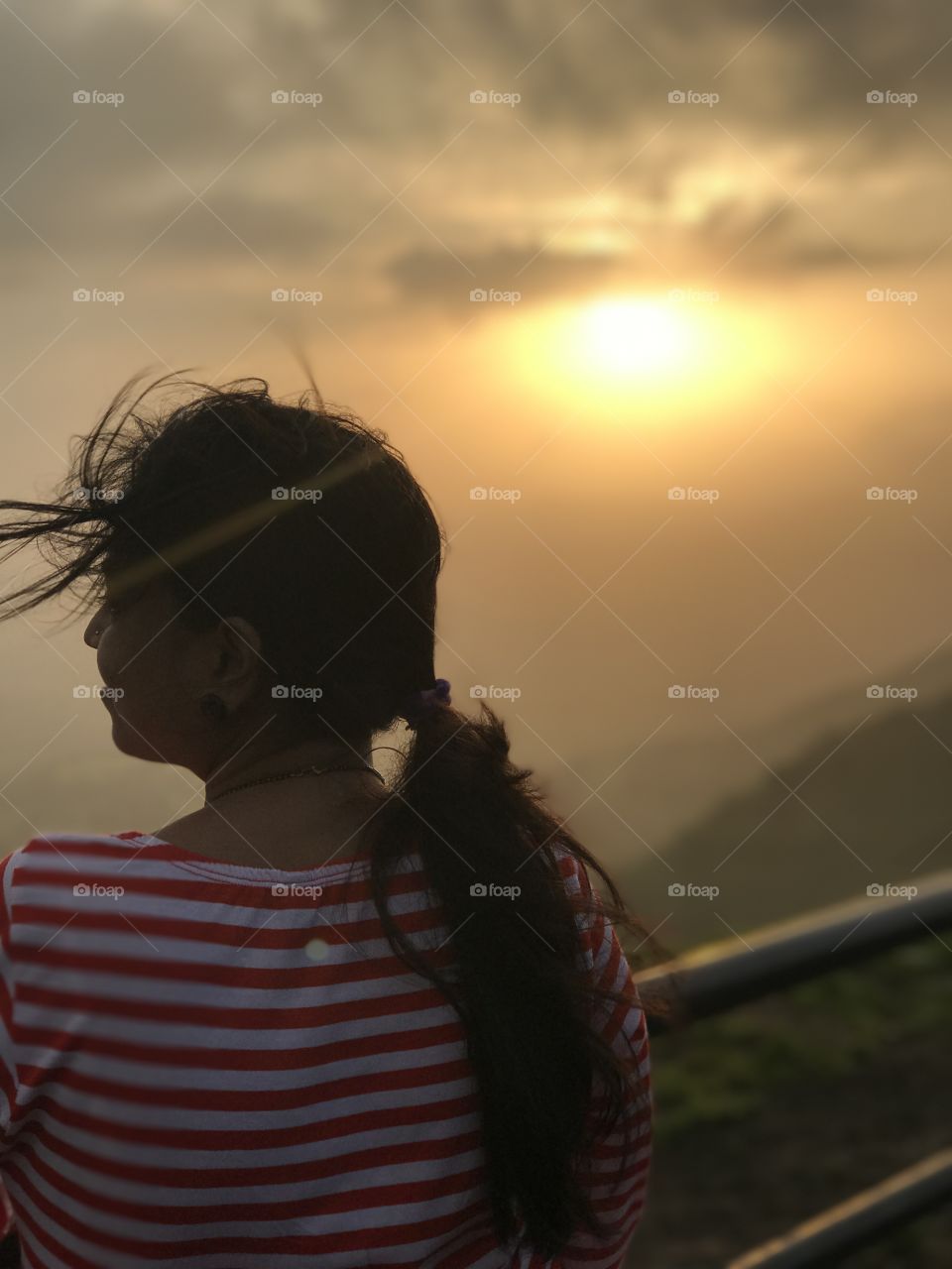 The moment she is standing on hill is the sun set time fresh air and mood is happy air passing over. The best moment I have found.