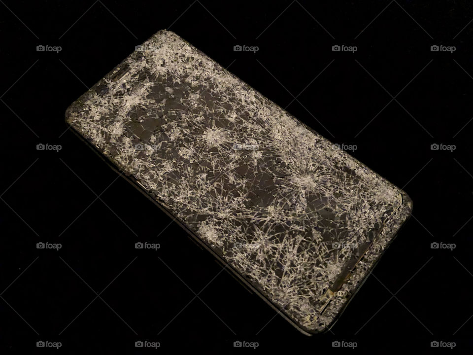 Mobile phone with broken glass on a black background