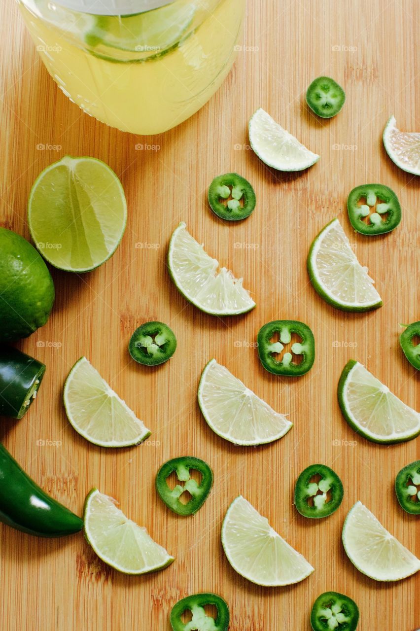 Flat lay of jalepeño pepper and lime with slices of each to flavor a quart-size mason jar of kombucha, all arranged on a bamboo cutting board 