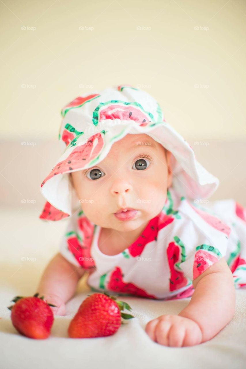 A Baby In A Hat With A Strawberry