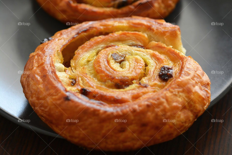 Danish raisin swirls on a black plate.