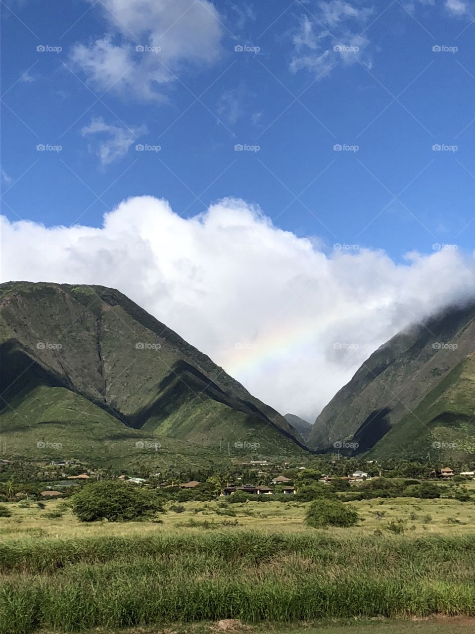 A rainbow stretches across the deep valleys in Maui, HI.