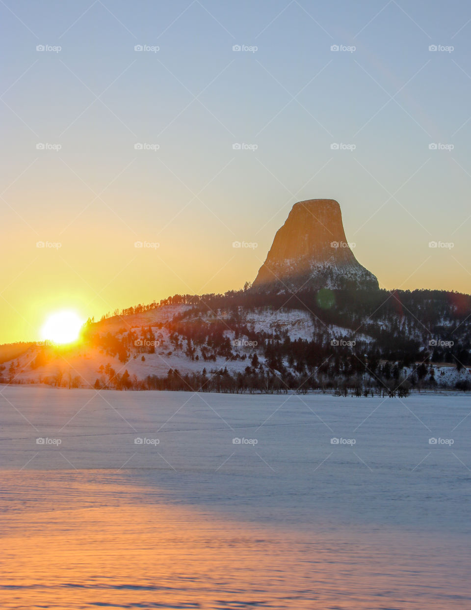 Devil's Tower in the snow at sunset. 