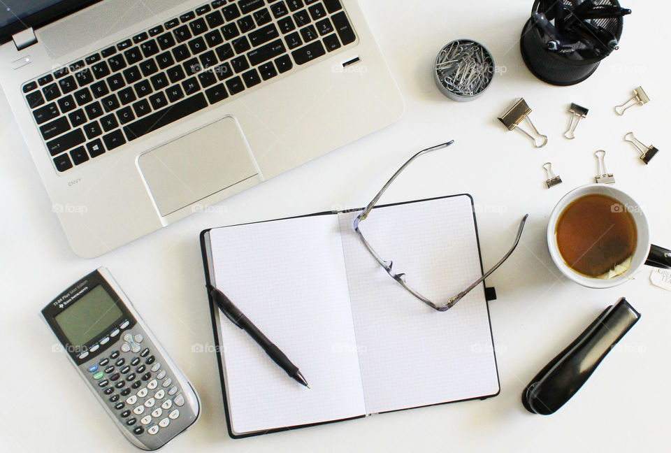 A desktop flat lay that include laptop, stationery, journal