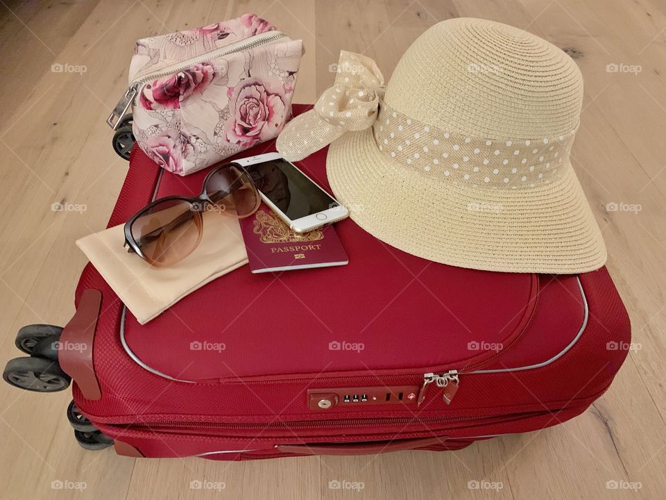 Suitcase with hat, passport, phone, purse and cooling glass 