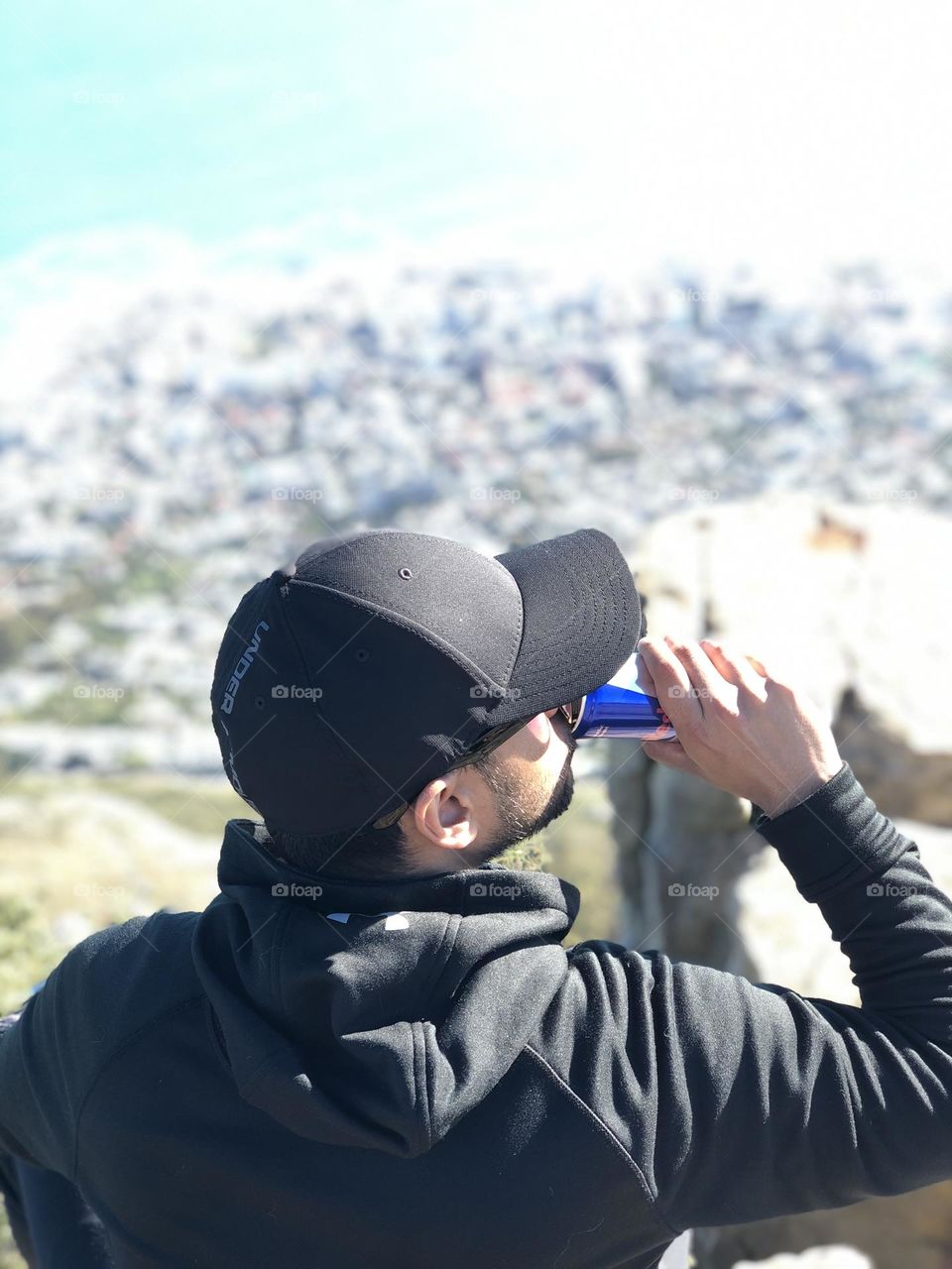 A refreshing drink after a long hike. His reward, the breathtaking scenery surrounding the top of lions head.