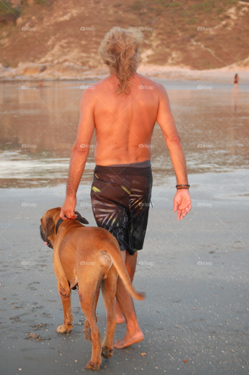 Man walking in the beach with his dog 