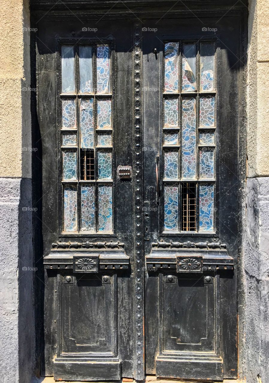 Symmetry of old doors decorated with colourful glass. 