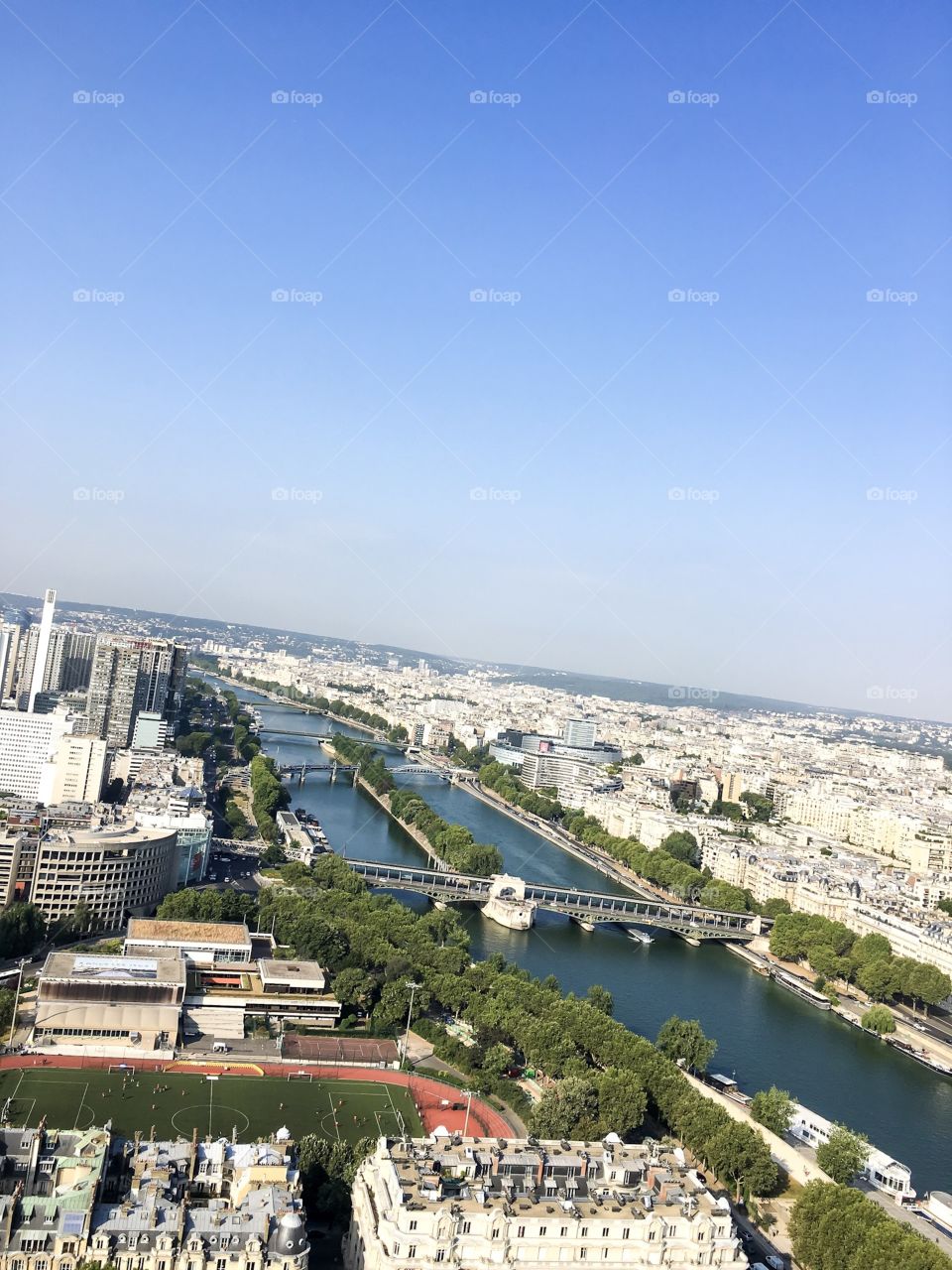 Paris from the Eiffel Tower. The sky is clear and blue, there is a great view of the Seine.
