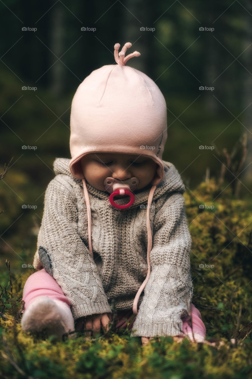 Baby sitting on forest ground with binary